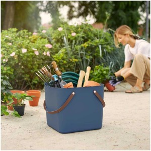 Multibag blu Rotho Albula (40 l) con attrezzi da giardinaggio; donna che pianta sullo sfondo.