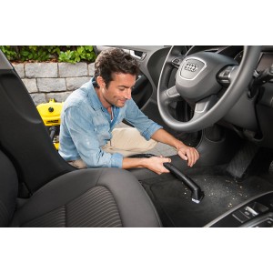 Homme nettoyant l'intérieur de sa voiture avec un kit de brosses Kärcher et un aspirateur.