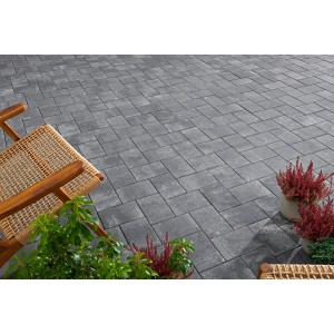 Pavés en béton Vero posés en gris anthracite nuancé, décorés avec des meubles de jardin et des plantes.