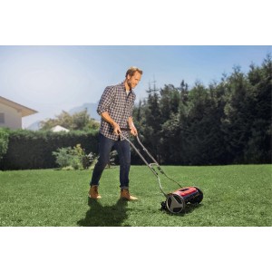 Uomo che taglia l'erba con rasaerba manuale rosso Einhell GE-HM 38 S in giardino.