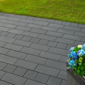 Dalles de pavage Kann Vero Maxx graphite (40x20x7,5 cm) posées avec pot de fleurs et pelouse en arrière-plan.