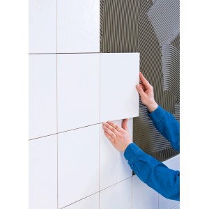 Anbringen einer weißen Fliese mit Knauf Fliesenkleber Superkleber Grau an einer Wand.