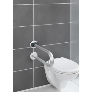 Barre d'appui rabattable Wenko Secura Premium en aluminium à côté de toilettes sur un mur gris.