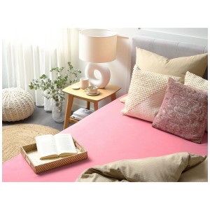 Drap-housse corail Janbu (160x200 cm) en coton sur un lit.