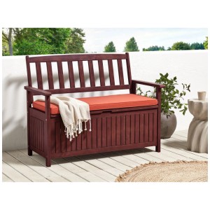 Banc de jardin Beliani Sovana en acacia marron foncé avec rangement et coussin orange.