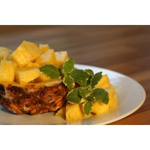 Blu Bio-Ananas-Minze en pot, décorée de morceaux d'ananas sur une assiette.