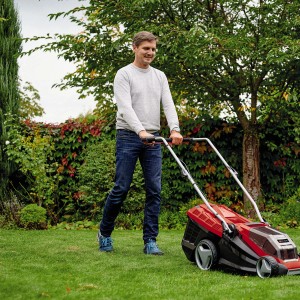 Homme tondant la pelouse avec la tondeuse à batterie Einhell Power X-Change GE-CM 36/36 Li avec batteries dans le jardin.