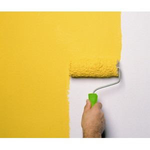 Hand streicht Wand mit gelbem Vestanroller, 18 cm Farbroller für glatte Flächen.
