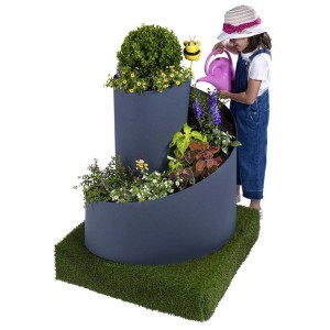 Spirale à herbes Gartec (Ø 80 cm) avec des plantes et un enfant qui arrose.