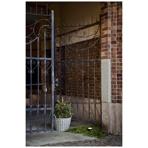 Catena luminosa LED Star Trading, 180 LED dorati-caldi su un cancello in area esterna.