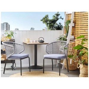 Ensemble bistro Beliani Palmi gris : table avec deux chaises et coussins pour balcon ou terrasse.