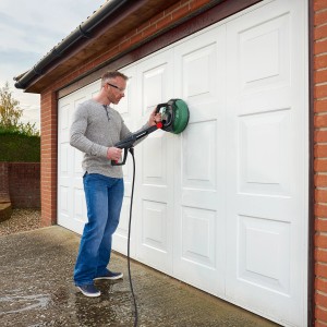 Homme nettoyant porte de garage avec le nettoyeur multi-surfaces Bosch Aquasurf 280.