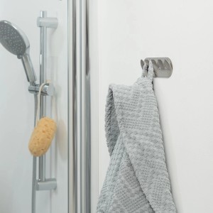 Porte-serviettes Tiger Rack Round en acier inoxydable brossé avec serviette grise dans la salle de bain.