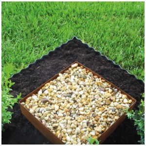 Bordure de pelouse ondulée Bellissa en métal galvanisé, utilisée dans une pelouse et un parterre de fleurs avec des pierres.
