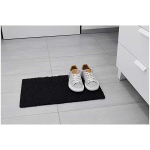 Schwarze Diaqua Duschmatte Noodles 40x60 cm vor hellem Badschrank mit Schuhen.