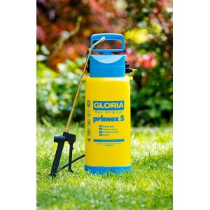 Pulvérisateur à pression Gloria Primex 5 jaune et bleu avec lance en laiton dans un jardin.