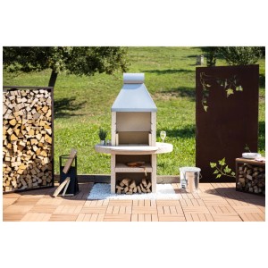 Barbecue-cheminée Nouvel Montagna en acier et béton blanc avec rangement pour bois dans le jardin.