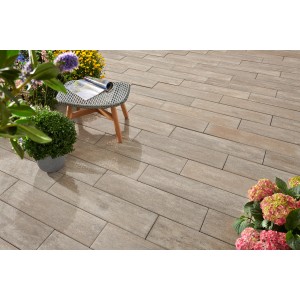 Pannelli per esterni Kann Rayon Sienna-Nuanciert 80x20x7,5 cm posati su terrazza con tavolo e piante.