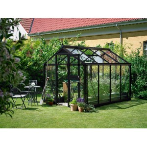 Serra Juliana Compact 6 antracite in giardino, con piante e attrezzi da giardinaggio.