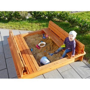 Sabbiera in legno color miele con copertura pieghevole e bambino che gioca.