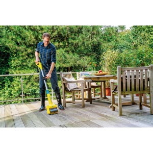 Uomo pulisce terrazza in legno con spazzola Gloria Universal. Utensile da giardino in uso.