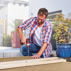 Homme vissant du bois dans le jardin avec une perceuse-visseuse sans fil Einhell 12 V TE-CD 12/1 Li.