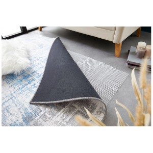 Grille antidérapante pour tapis Andiamo 120x180 cm sous un tapis sur un sol clair.