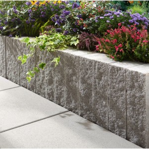 Pierre de mur Montania gris argenté utilisée comme bordure de parterre surélevé avec des plantes.