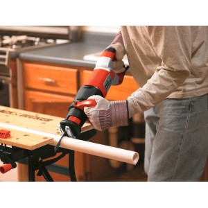 Scie sabre Black+Decker RS1050EK coupant un tuyau. Scie électrique avec boîtier rouge.
