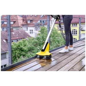 Kärcher PCL 4 pulitore per terrazze in uso su terrazza in legno. Dispositivo di pulizia in giallo/nero.