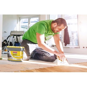 Mann verlegt Parkett mit Soudal Parkettkleber 68A aus einem gelben 15 kg Eimer.