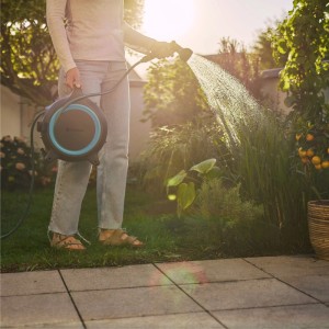 Donna che innaffia il giardino con Gardena Schlauchbox MoveMatic 12,5 m. Carrello avvolgitubo mobile.