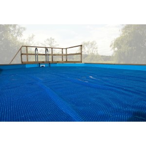 Bâche thermique bleue Weka sur piscine en bois massif, avec effet solaire pour le chauffage.