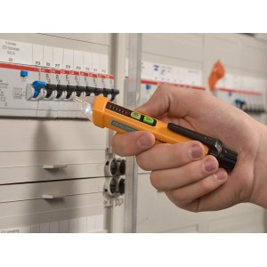 Testeur de tension sans contact jaune (12-1000V) utilisé sur un boîtier de fusibles.