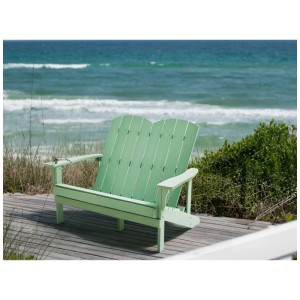 Banc de jardin Adirondack vert clair en bois composite pour deux sur terrasse face à la mer.