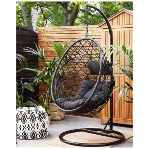 Sedia sospesa nera Beliani Alatri con struttura in polyrattan in giardino.