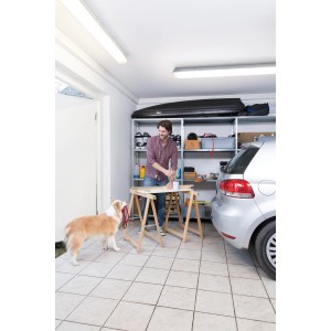 Uomo lavora in garage con lampada stagna a LED Osram. Cane guarda.
