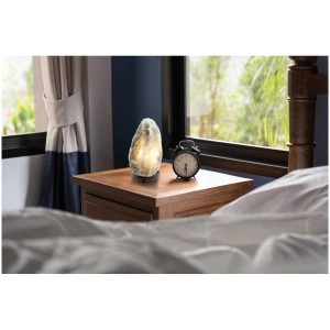 Lampada da tavolo Globo Stone in cristallo di sale, grigia, su un comodino. Lampada da tavolo di design per luce d'atmosfera.