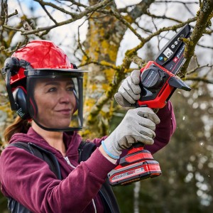 Femme utilisant une tronçonneuse à batterie Einhell GE-PS 18/15 Li pour tailler un arbre.