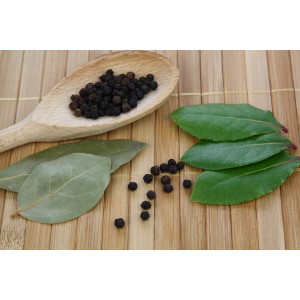 Laurier Blu avec feuilles et grains de poivre sur une cuillère en bois et fond en bambou.