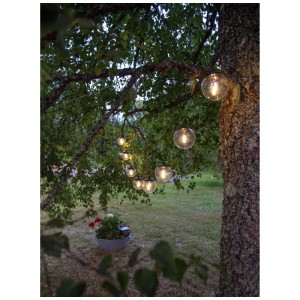 Solar-Lichterkette Globe, schwarz, mit warmweissem Licht an einem Baum im Garten.