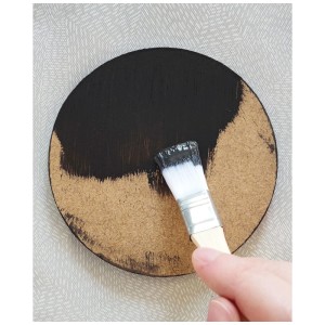 Applicazione di vernice nera con un pennello su un disco di legno del set Aladine Dot Painting.