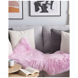 Rosa Schaffell-Teppich Uluru Langhaar (100-110cm) auf Sofa, mit Buch und Tasse auf Tisch.