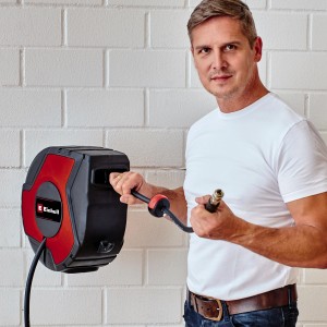 Enrouleur de tuyau Einhell TC-PH 150 avec homme devant un mur blanc. Accessoire pour compresseurs.
