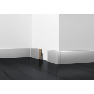 Plinthe blanche Cubica (40x18x2500 mm) sur un mur avec un sol foncé.