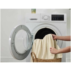 Coperta riscaldante beige Sonnenkönig Emmy in pile di flanella davanti alla lavatrice. Lavabile a 30°C.