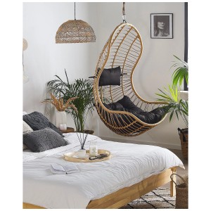 Sedia sospesa Beliani Pineto in rattan, aspetto naturale con cuscini neri in camera da letto.
