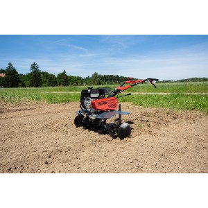 Motobineuse thermique Al-Ko MH 1150 Comfort avec boîtier rouge et lames noires sur terrain agricole.