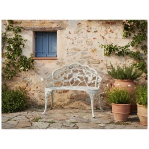 Banc de jardin Beliani Piura en aluminium blanc avec décorations florales devant un mur en pierre.
