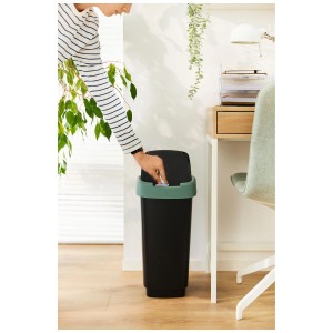 Rotho Swingeimer Twist, anthrazit-grün, 50L. Person wirft Papier in den Mülleimer mit Schwingdeckel.